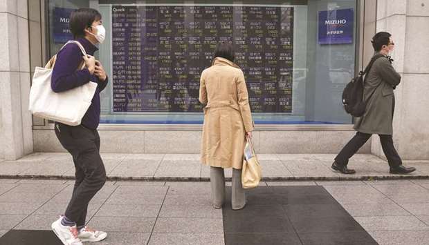 A pedestrian looks at an electronic stock board outside a securities firm in Tokyo. Japanese shares gained 0.1% at 23,827.18 points after sliding 1.2% since Monday.