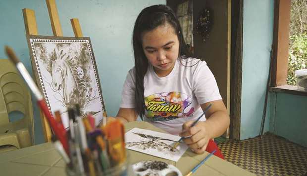 Filipina artist Janina Sanico uses volcanic ash she found in her yard to paint images of Taal volcano inside her home in Tanauan, Batangas Province, yesterday.