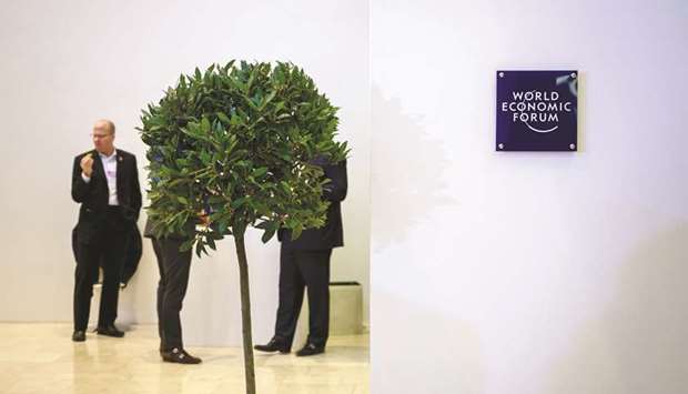 People stand behind a tree installed as decoration inside the Congress centre, during the World Economic Forum (WEF) annual meeting in Davos on Thursday.