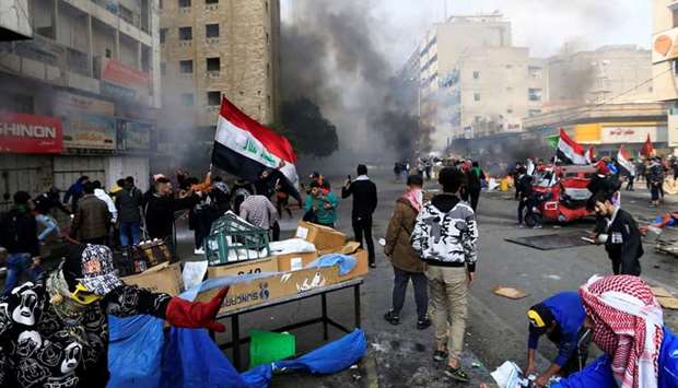 Demonstratos are seen amongst smoke rising from burning tents as Iraqi security forces raid at Tahrir Square during ongoing anti-government protests in Baghdad