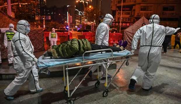 Medical staff members wearing protective clothing to help stop the spread of a deadly virus which began in the city, arrive with a patient at the Wuhan Red Cross Hospital in Wuhan