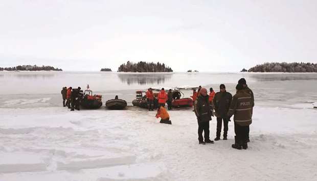 A Surete du Quebec handout image of rescue personnel yesterday stand on the the banks of Lake Saint-Jean, Quebec, preparing for recovery operations for four French snowmobilers.