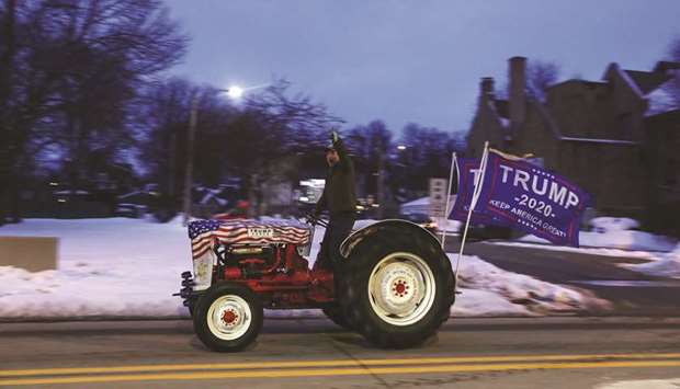 A supporter of President Donald Trump rides a tractor outside the Democratic 2020 US presidential candidate and US Senator Bernie Sanders (I-VT) campaign rally venue in Ames, Iowa, on Saturday evening.