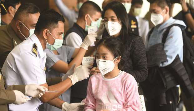 Health workers use infrared thermometers to check the temperature of tourists who arrive at Bangkoku2019s Don Mueang Airport yesterday.