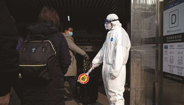 Security personnel wearing protective clothing to help stop the spread of a deadly virus, stands at a subway station in Beijing yesterday.