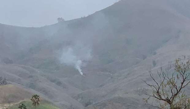 Smoke rises amid foggy weather from the site of a helicopter crash that killed former NBA star Kobe Bryant, his daughter Gianna and seven others, along a hillside in Calabasas, California, yesterday