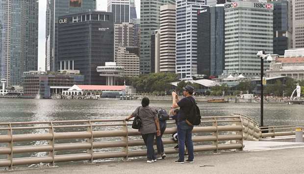 A man takes a photo as the financial business district looms in the background in Singapore. The city-state is currently forecasting growth in a wide range of 0.5-2.5% this year.