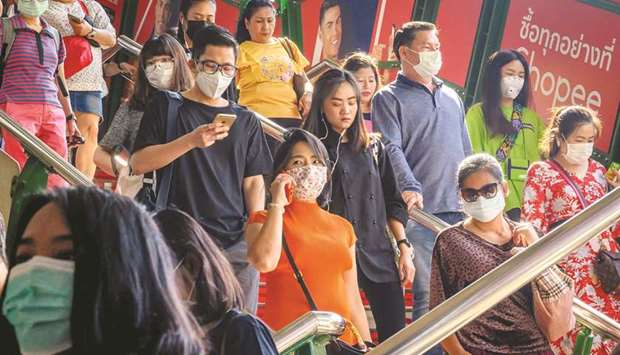 People with face masks arrive at a BTS Sky train station in Bangkok yesterday.
