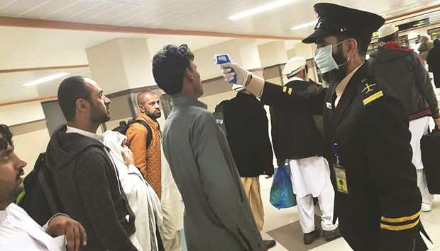 An airport official checks the temperature of a passenger upon his arrival at the Bacha Khan International Airport in Peshawar.