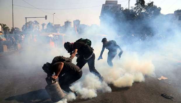Demonstrators throw tear gas back during ongoing anti-government protests in Baghdad