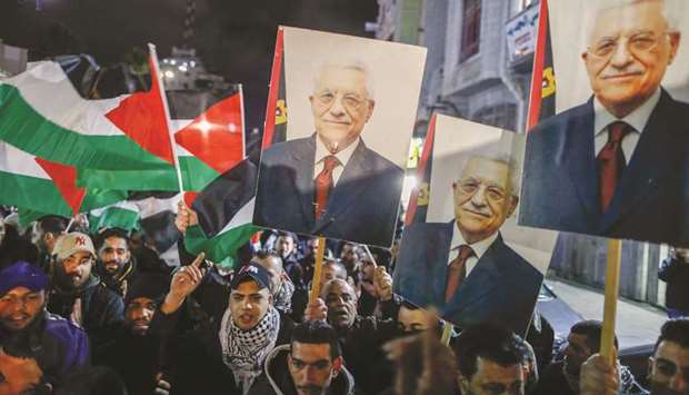 Palestinian protesters wave the national flag and a portrait of president Mahmoud Abbas during a demonstration in the West Bank city of Ramallah yesterday, against US President Donald Trumpu2019s peace plan proposal.
