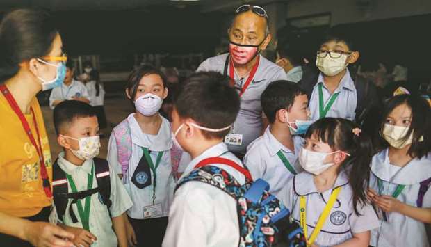 Guardians and students wear masks amid a health scare over a new virus that has infected thousands since emerging in China, in a Chinese school in Quezon City, Metro Manila, yesterday.