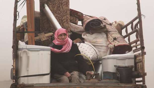 A Syrian man sits with belongings in the back of a truck passing through the town of Ariha, in the northern countryside of Idlib province yesterday, as people flee from the south of Idlib during an ongoing offensive by government forces.