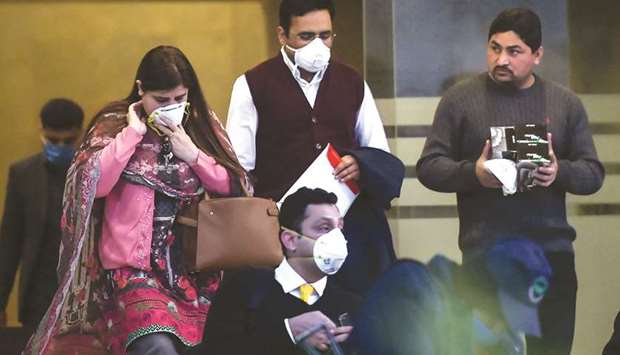 People wearing protective facemasks leave a Pakistan-based Chinese company in Islamabad, following instructions from Pakistani authorities to take preventive measures against the coronavirus.