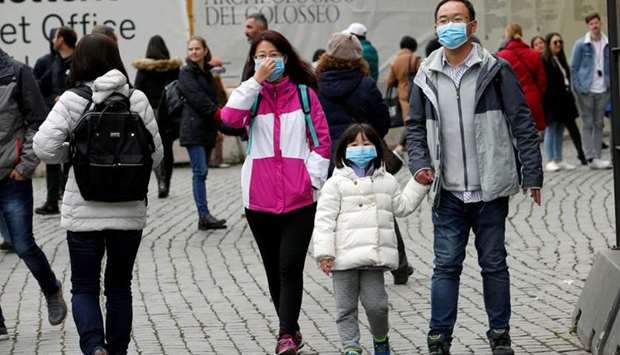 Tourists wearing protective masks walk past the Colosseum, after two cases of coronavirus were confirmed in Italy, in Rome