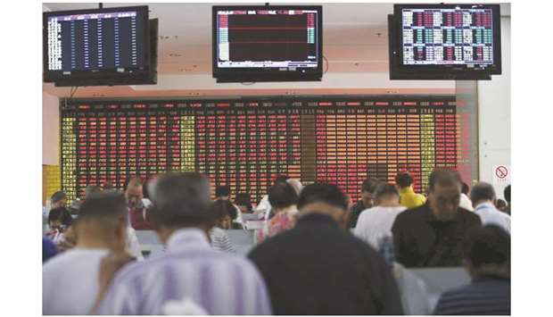 Investors look at computer screens in front of an electronic board showing stock information at a brokerage house in Shanghai. The Composite index closed down 0.1% to 3,083.79 points yesterday.