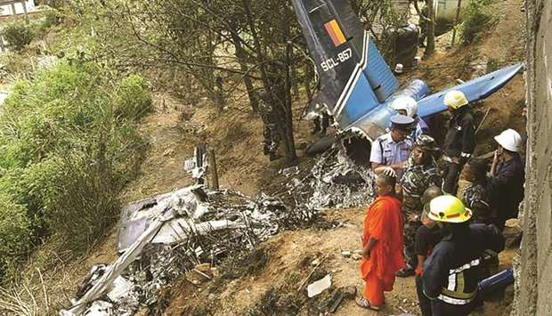 Rescue workers inspect the wreckage of a Sri Lankan air force plane that crashed in Haputale yesterday.