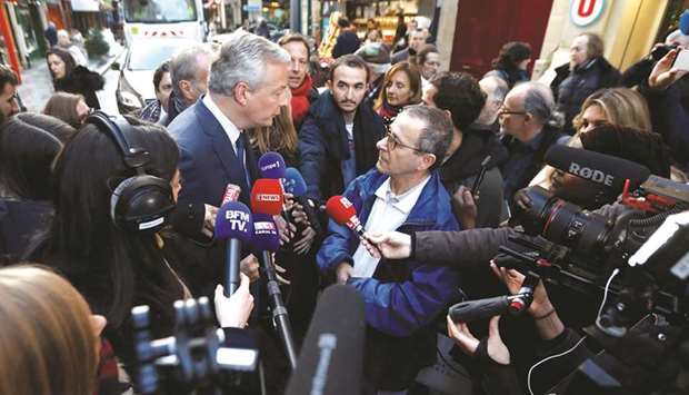 Finance Minister Le Maire speaks with a local resident while visiting shopkeepers, restaurateurs and hotel operators in Paris to assess the economic impact of nationwide strikes on pensions reform.