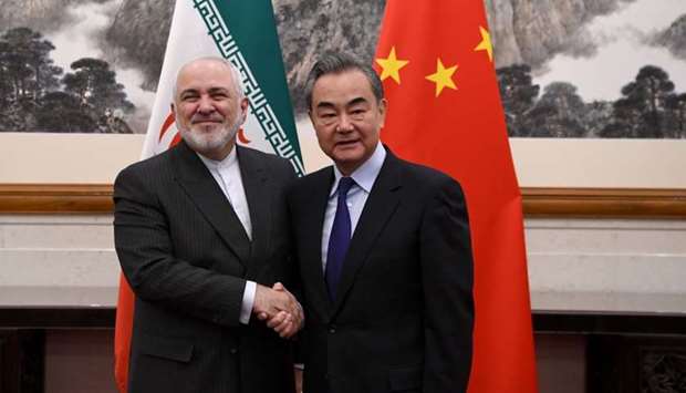 China's Foreign Minister Wang Yi (R) shakes hands with Iran's Foreign Minister Mohammad Javad Zarif during their meeting at the Diaoyutai State Guest House in Beijing on December 31, 2019
