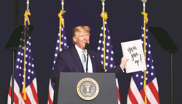 President Donald Trump holds a u2018Never give up!u2019 sign as he gives a speech to supporters in Miami on Friday night.