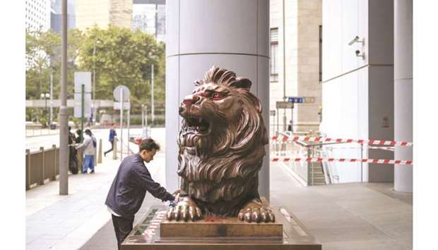 A cleaner wipes a vandalised lion statue outside the HSBC Holdings headquarters in Hong Kong. The bank is working to improve relations with China, launching a public-relations offensive aimed at leaders in Beijing after missing out on several business licences.