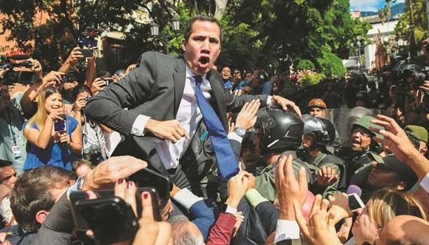 Venezuelan opposition leader and self-proclaimed acting president Juan Guaido is surrounded by journalists on his way to the National Assembly in Caracas yesterday.
