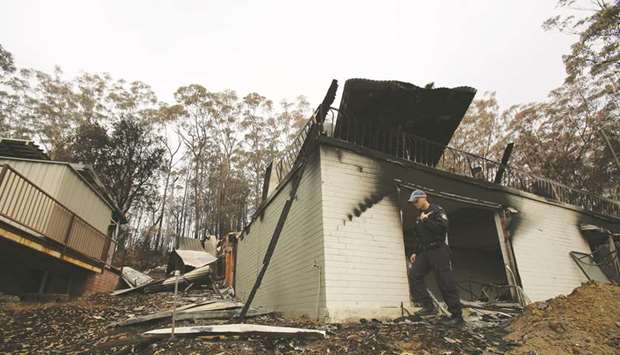 A police officer patrols a damaged property during bushfire season in Lake Conjola, Australia.