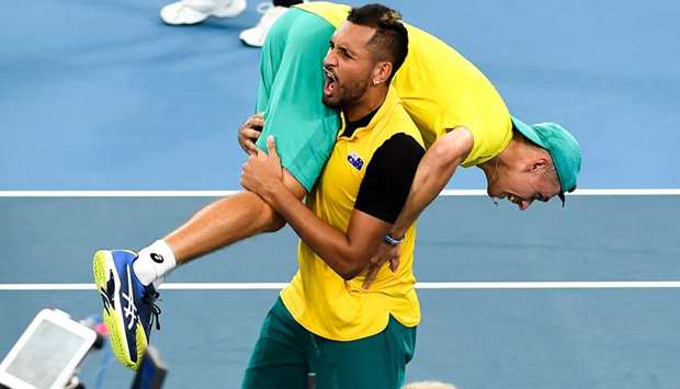 Nick Kyrgios of Australia carries teammate Alex de Minaur after winning their doubles match against Jamie Murray and Joe Salisbury of Britain at the ATP Cup in Sydney yesterday. (AFP)