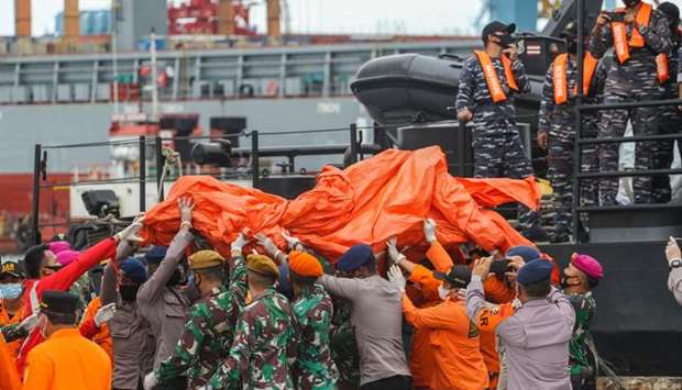 Rescue workers carry recovered debris at the port in Jakarta during the search operation for Sriwijaya Air flight SJY182 which crashed after takeoff from Jakarta on January 9