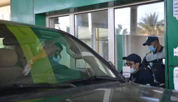 Saudi customs officials check the documents of a visitor travelling by car into Saudi Arabia from Qatar through the Salwa crossing between the two Gulf countries on January 10, 2021. Qatar and Saudi Arabia reopened their land border the previous day as they restored ties following a landmark deal to end a three and a half year rift. AFP