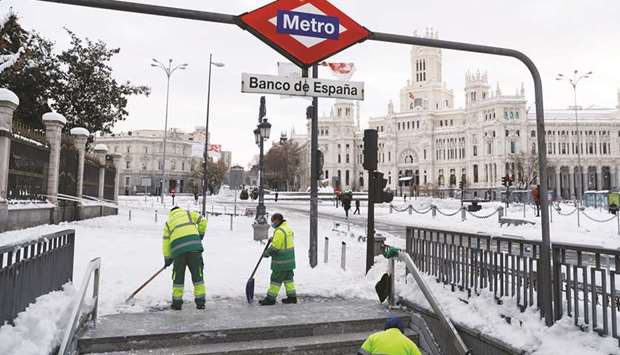 Workers shovel snow at the entrance to the metro station, with the City Hall building in the background, in Madrid yesterday.
