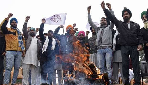 Farmers burn copies of recent agricultural reforms as they celebrate Lohri festival to demonstrate against the central government on the outskirts of Amritsar