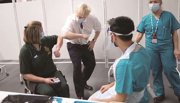 First Responder Caroline Cook elbow-bumps Prime Minister Johnson while she waits for her vaccination at a Covid-19 vaccination centre at Ashton Stadium in Bristol.