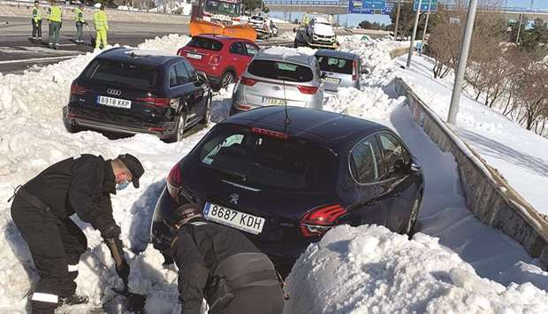 Members of Spainu2019s military unit (UME) shovel snow to open a pass next to cars accumulated on M-40 highway following heavy snowfall in Madrid.