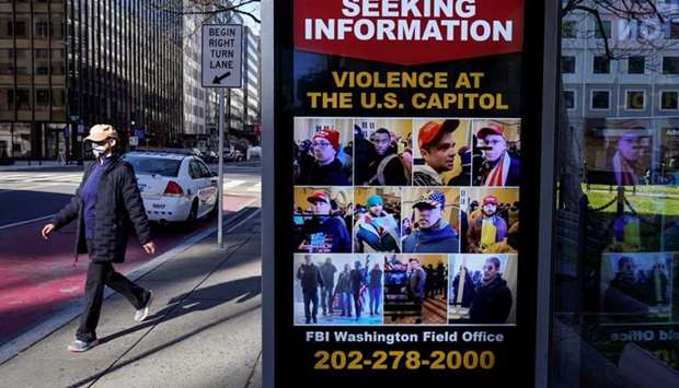 A pedestrian walks past a sign at the bus stop from the FBI seeking information on supporters of US President Donald Trump who stormed the US Capitol in Washington.