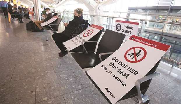 Social distancing signs are displayed on seats in the check-in area at the Heathrow Airport in London. The resurgence of the virus and associated restrictions weighed on air travel recovery progress across many domestic and international markets.