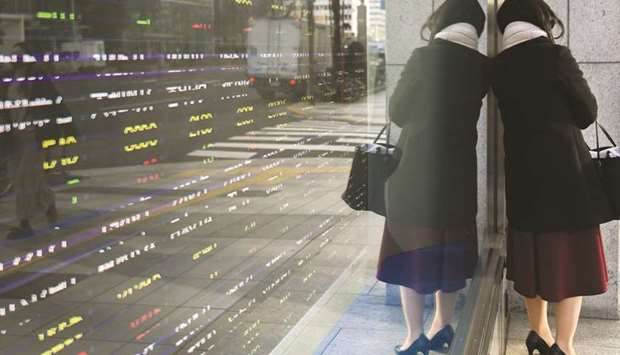 A woman stands against an electronic stock board outside a securities firm in Tokyo. The Nikkei 225 closed 0.9% up at 28,698.26 points yesterday.