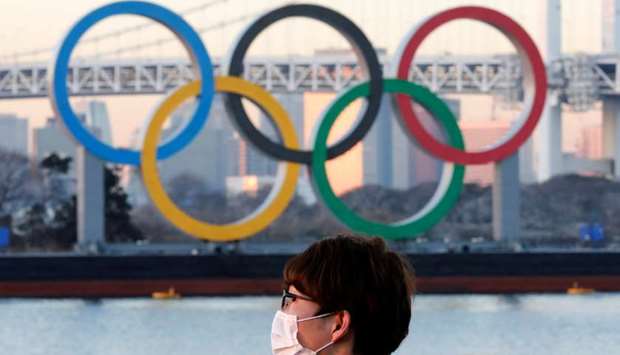 A man wears a protective mask amid the coronavirus disease (Covid-19) outbreak in front of the giant Olympic rings in Tokyo, Japan