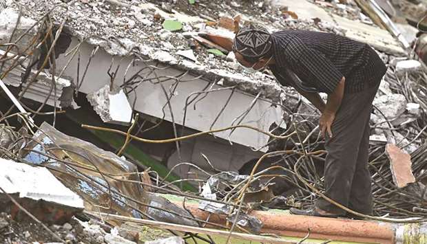 A man looks at the rubble of a collapsed building in Mamuju city.