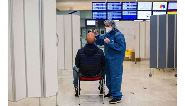 A health worker doing a Covid-19 swab test on an airline traveler at Charles de Gaulle airport, operated by Airport de Paris, in Roissy, France. Pre-departure testing is an added layer of protection to the strong measures many countries have already in place.