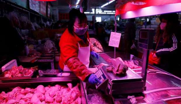 A vendor wearing a face mask following the coronavirus disease outbreak weighs a chicken at her stall inside a market in Beijing on January 15