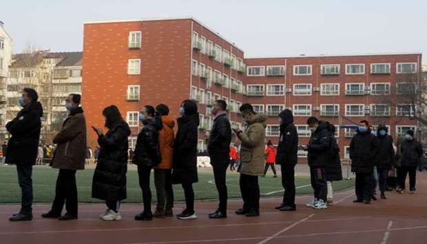 People line up to get their nucleic acid test on the sports ground of a school following the outbreak of the coronavirus disease in Beijing, China