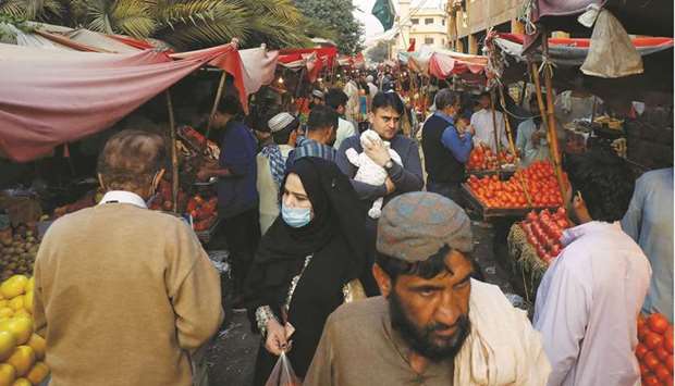 This picture taken last week shows people with and without masks walk along fruit stalls at a market in Karachi.