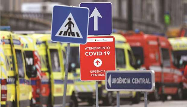 Signs are seen as ambulances carrying patients with the coronavirus disease are queued yesterday outside the Santa Maria Hospital in Lisbon.