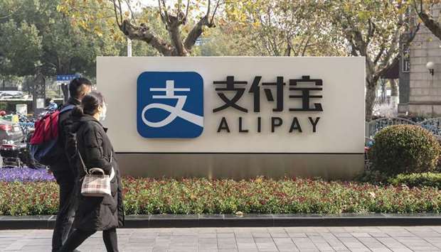 A pedestrian walks past an Alipay sign outside an Ant Group Co office building in Shanghai (file). Officials have unveiled a string of new rules to curb its booming financial technology industry and prevent any one firm from becoming too powerful. The measures upended a $35bn initial public offering by Ant Group in November.