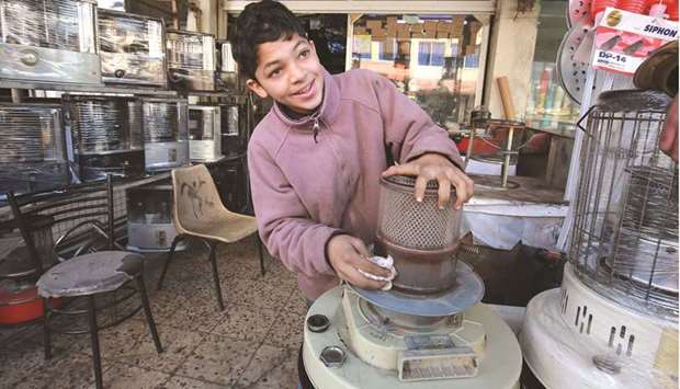       Jordanian teenager, Omar, 14, fixes a kerosene heater in a  workshop where he works in Amman.