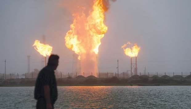 A man looks at flames rising from oil refinery pipes in Basra (file). Opecu2019s second-biggest producer will pump around 3.6mn barrels daily for the two months, according to Ali Nizar, the deputy head of SOMO.