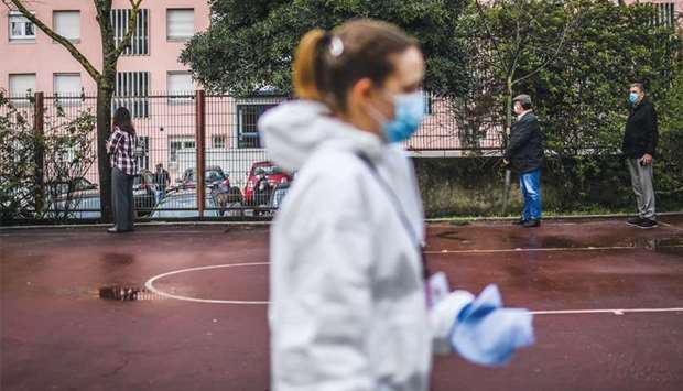 A cleaning employee walks past people queuing to vote in the Portuguese presidential election, at Lisbonu2019s Telheiras school, which was being used as a polling station.