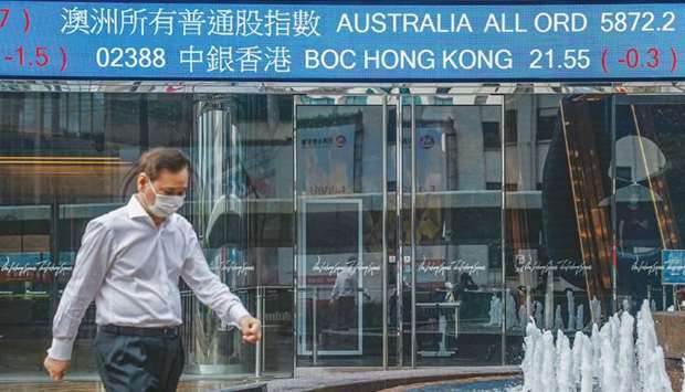 A pedestrian walks past a stock ticker at the Exchange Square complex, which houses the Hong Kong Stock Exchange, in Hong Kong (file). The Hang Seng ended 2.6% down at 29,391.26 points yesterday.