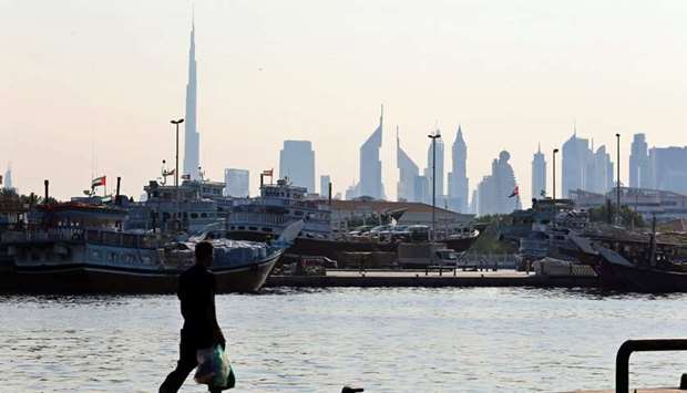 A man walks at the Dubai creek (file). Forecasts for economic recoveries in the six-member Gulf Cooperation Council in 2021 have been trimmed while expectations for gross domestic product declines last year were mixed in a quarterly Reuters survey of analysts released yesterday.